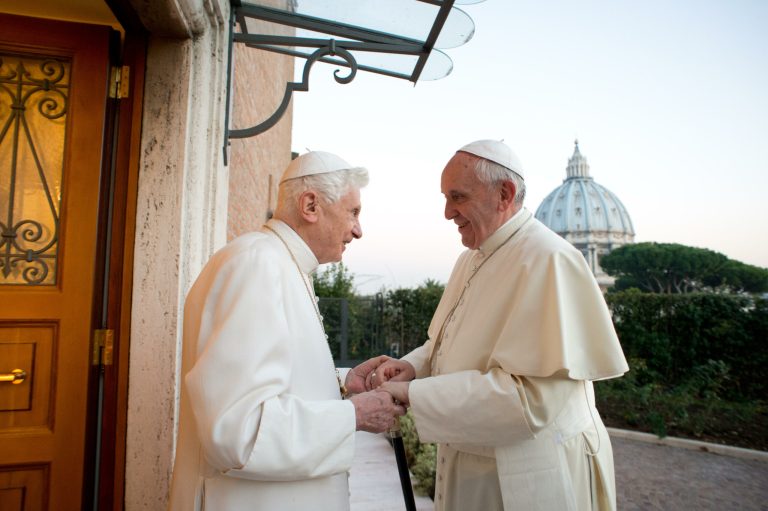 In this file picture provided by the Vatican newspaper L'Osservatore Romano on Dec. 23, 2013, Pope Emeritus Benedict XVI, left, welcomes Pope Francis as they exchanged Christmas greetings, at the Vatican. It was a holiday at the Vatican and Pope Benedict XVI was speaking in Latin at an arguably boring ceremony announcing new saints, so few people were paying much attention. But what Benedict said a year ago Tuesday changed the course of the 2,000-year-old Catholic Church and paved the way for the historic papacy of Pope Francis. In his soft voice and in a Latin that the cardinals present strained to understand, Benedict announced that he no longer had the 