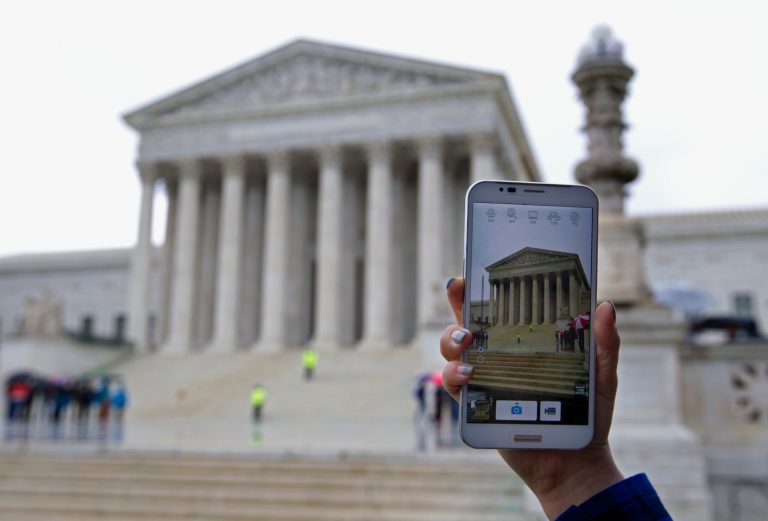 A Supreme Court visitor takes pictures with her cell phone outside the Supreme Court in Washington, Tuesday, April 29, 2014, during a hearing. The Supreme Court is considering whether police may search cellphones found on people they arrest without first getting a warrant. ( AP Photo/Jose Luis Magana)