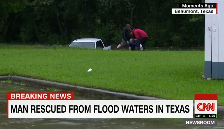 Griffin and another crew member are then seen pulling a man out of the truck onto the grass as the truck continued floating in the ditch. (Image courtesy screenshot)
