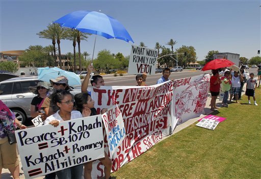 Demonstraters gather outside a Scottsdale, Ariz., resort to protest against Mitt Romney, who was speaking inside, and Arizona's controversial immigration law, SB1070 on Monday. AP Photo)