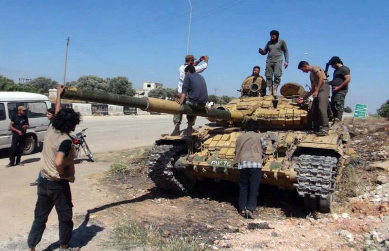 Edlib News Network/AP
Syrian rebels stand on top of a tank they took after storming the Iskan military base in Idlib province, northern Syria. A Pew poll released Monday showed that 70 percent of Americans don't want the U.S. to arm Syrian rebels.