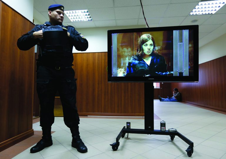 A policeman watches band member Nadezhda Tolokonnikova speaking on a TV screen in a hall outside a court room of the Moscow City Court where three members of the punk band Pussy Riot are set to make their case before a Russian appeals court that they should not be imprisoned, in Moscow, Wednesday. Oct. 10, 2012. Their impromptu performance inside Moscow's main cathedral in February came shortly before Putin was elected to a third term. The three women were convicted in August of hooliganism motivated by religious hatred and sentenced to two years in prison. (AP Photo/Sergey Ponomarev)
