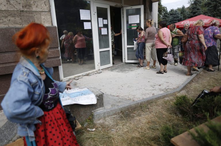 Local residents stand in line to get benefit payments outside the  rebel headquarters in Donetsk, eastern Ukraine, Tuesday, Aug. 19, 2014.  A crowd formed outside the rebel headquarters, once the Donetsk region administrative building, in Donetsk amid rumors that pension and disability payments and child assistance were being given out. (AP Photo/Max Vetrov)