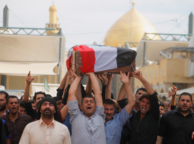 Mourners chant slogans against the al-Qaida breakaway group Islamic State of Iraq and the Levant (ISIL), while carrying a flag-draped coffin of Ahmed Marzouk an Iraqi officer who was killed, said his family, in a fake checkpoint on Thursday, during his funeral procession in the Shiite holy city of Najaf, 100 miles (160 kilometers) south of Baghdad, Iraq, Friday, May 16, 2014. Bombings and shootings around Iraq's capital, including a deadly attack involving militants using a fake checkpoint to target army officers, killed and wounded dozens of people on Thursday, officials said. (AP Photo/ Jaber al-Helo)