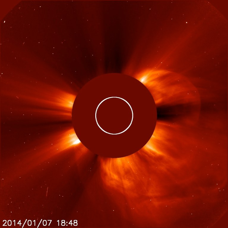 In this Tuesday, Jan. 7, 2014 image made available by NASA, a giant cloud of solar particles, a coronal mass ejection, explodes off the sun, lower right, captured by the European Space Agency and NASA's Solar and Heliospheric Observatory. The sun is obscured to show the atmosphere around it. The solar flare caused the cancellation of a launch to the International Space Station on Wednesday, Jan. 8, 2014. (AP Photo/ESA, NASA - SOHO)