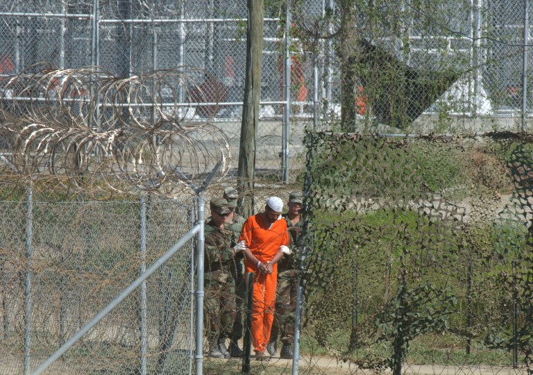 In this March 1, 2002 file photo, a detainee is escorted to interrogation by U.S. military guards at Camp X-Ray at Guantanamo Bay U.S. Naval Base, Cuba. (AP Photo/Andres Leighton, File)