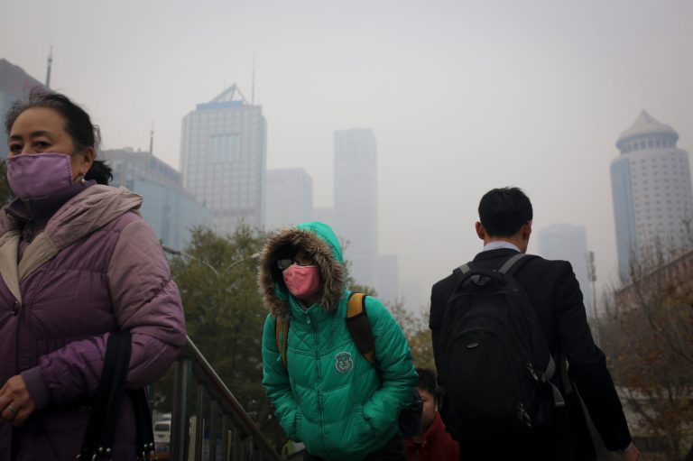 People wearing masks to protect themselves from pollutants walk on a pedestrian overhead bridge as city skylines are shrouded with haze in Beijing Wednesday, Nov. 19, 2014. (AP Photo/Andy Wong)
