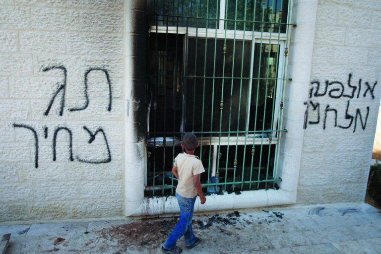 A Palestinian child stands outside a vandalized mosque in the West Bank town of Jabaa, near Ramallah, Tuesday, June 19, 2012. By July 1, the government has committed to destroying 30 apartments settlers built illegally on privately held Palestinian land. Acts of vandalism against Palestinian property have been expected ahead of that date because radical settlers routinely attack Palestinian targets in retaliation for government settlement policy they oppose. From left to right Hebrew writing reads, 