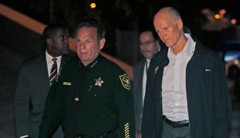 Florida Gov. Rick Scott, right, walks with Sheriff Scott Israel of Broward County to a news conference near Marjory Stoneman Douglas High School in Parkland, Fla., where a former student is suspected of killing at least 17 people Wednesday. Israel told reporters Friday, 