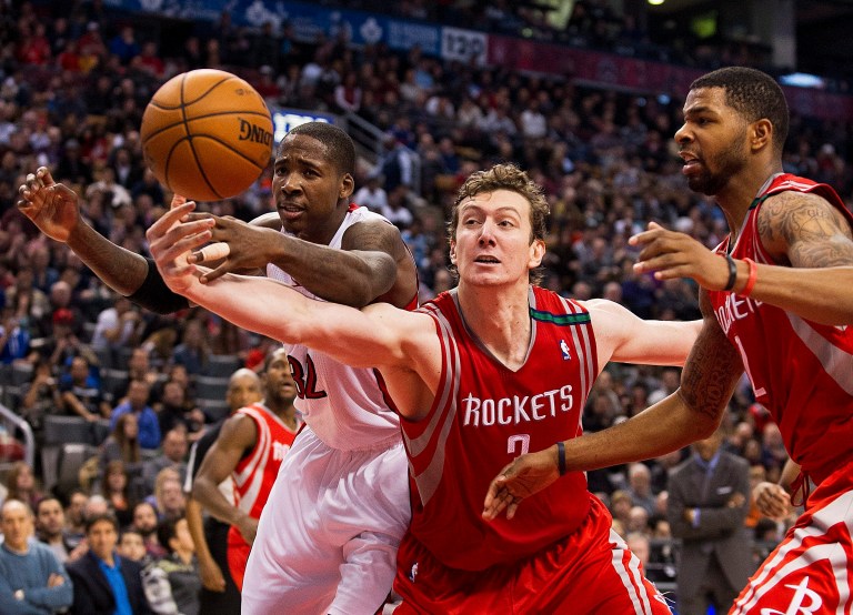   Houston Rockets' Omer Asik, center, reaches for the ball against Toronto Raptors' Ed Davis during second-half NBA basketball game action in Toronto, Sunday, Dec. 16, 2012. (AP Photo/The Canadian Press, Aaron Vincent Elkaim)  