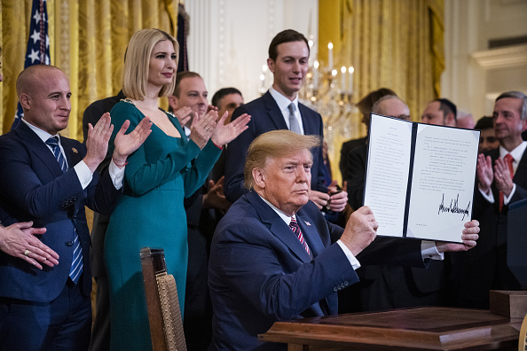 U.S. President Donald Trump, center, holds a signed executive order during a Hanukkah reception at the White House in Washington, D.C., U.S., on Wednesday, Dec. 11, 2019. He is flanked by Ivanka Trump and Jared Kushner.