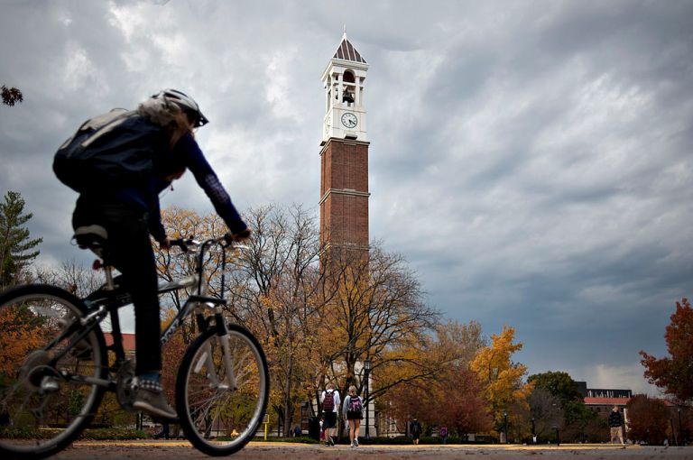 A student rides a bicycle past the bell tower on the campus of Purdue University in West Lafayette, Indiana.