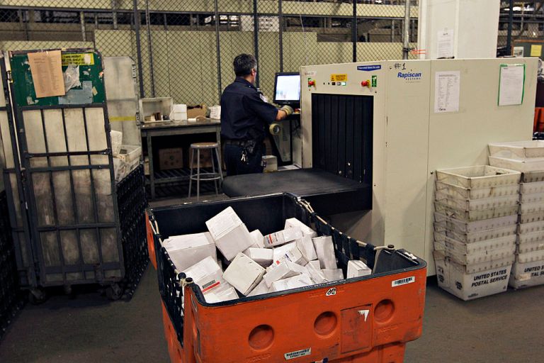 A U.S. Customs and Border Protection officer examines packages with an x-ray machine in the enforcement area of the U.S. Postal Service John F. Kennedy Airport Mail Center in Jamaica, New York, U.S., on Thursday, Jan. 10, 2008. 