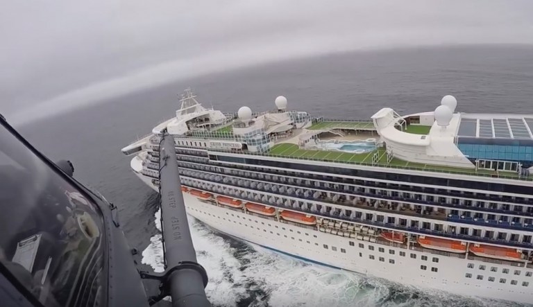 In this image from video, provided by the California National Guard, a helicopter carrying airmen with the 129th Rescue Wing flies over the Grand Princess cruise ship off the coast of California Thursday, March 5, 2020. Scrambling to keep the coronavirus at bay, officials ordered a cruise ship with 3,500 people aboard to stay back from the California coast Thursday until passengers and crew can be tested, after a traveler from its previous voyage died of the disease and at least two others became infected. Airmen lowered test kits onto the 951-foot (290-meter) Grand Princess by rope as the vessel lay at anchor off Northern California, and authorities said the results would be available on Friday. Princess Cruise Lines said fewer than 100 people aboard had been identified for testing.