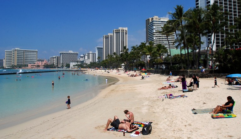 FILE - In this March 13, 2017, file photo, people relax on the beach in Waikiki in Honolulu. Many sunscreen makers could soon be forced to change their formulas or be banned from selling lotions in Hawaii. Hawaii state lawmakers on Tuesday passed a measure that would ban the local sale of sunscreens containing oxybenzone and octinoxate by 2021 in an effort to protect coral reefs.