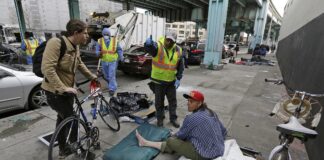 In this Feb. 26, 2016, photo, a San Francisco city worker tells a homeless man that the area next to him is about to be washed and points to an area he might want to move to.