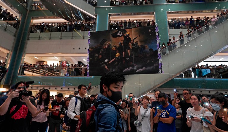 A protester raises a painting of protesters after they sing a theme song written by protesters "Glory be to thee" at a shopping mall in Hong Kong Wednesday, Sept. 11, 2019.