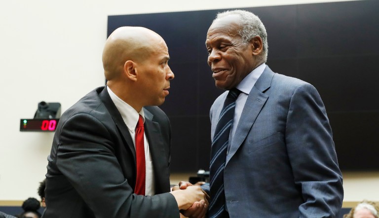 Democratic Presidential candidate Sen. Cory Booker, D-NJ, left, greets Actor Danny Glover, before they testify about reparations for the descendants of slaves, during a hearing before the House Judiciary Subcommittee on the Constitution, Civil Rights and Civil Liberties, at the Capitol in Washington, Wednesday, June 19, 2019.