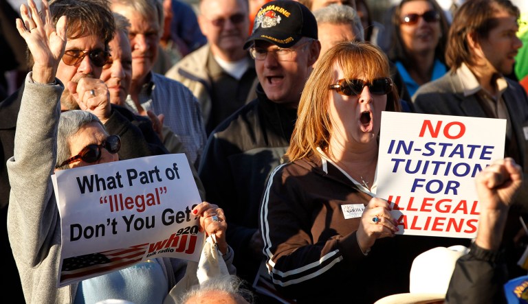 Demonstrators display placards during a rally in front of the Statehouse, in Providence, R.I., Wednesday, Oct. 5, 2011. Several hundred critics of Gov. Lincoln Chafee, including state lawmakers, tea party activists and others, criticized a new policy allowing in-state tuition for illegal immigrants at public colleges during the rally.