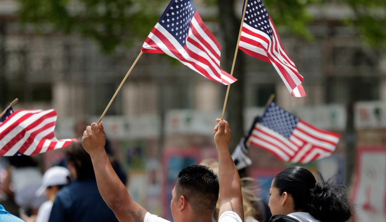 A protester holds American flags as he marches during a rally in support of undocumented immigrants in Charlotte, N.C., Monday, May 1, 2017.