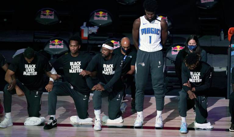 Orlando Magic's Jonathan Isaac (1) stands as others kneel before the start of an NBA basketball game between the Brooklyn Nets and the Orlando Magic Friday, July 31, 2020, in Lake Buena Vista, Fla. 