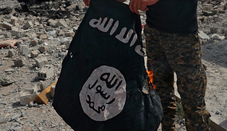 A fighter of the Christian Syriac militia that battles Islamic State militants under the banner of the U.S.-backed Syrian Democratic Forces, burns an IS flag on the front line on the western side of Raqqa, northeast Syria, Monday, July 17, 2017. U.S.-backed Syrian fighters fought Islamic State militants in the heart of Raqqa, the extremists' self-styled capital, as scores of civilians fled areas controlled by the group.