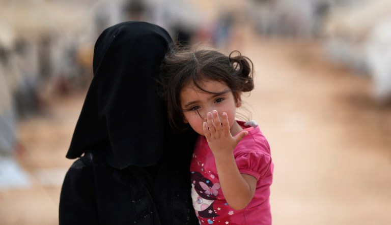 A Syrian woman carries a child in a squalid camp for internally displaced people in al-Bab, northern Syria, Tuesday, May 29, 2018.