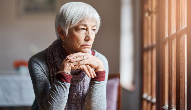 Shot of a senior woman looking out the window.