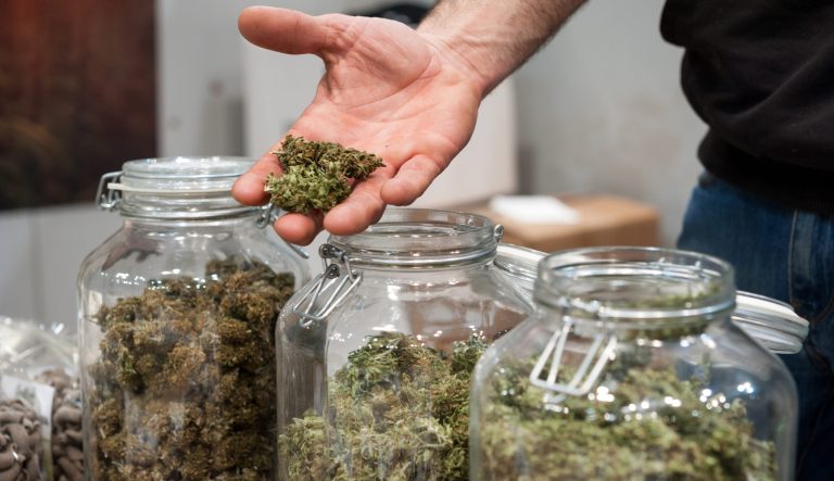 Glass jar of marijuana for sale at a market stall.