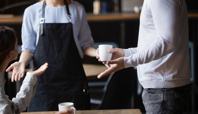 Customers argue with a waitress in a coffeehouse.