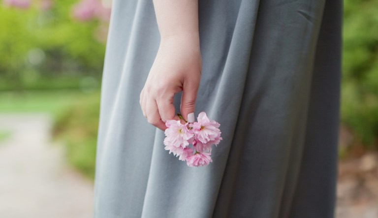 Woman holds pink sacura flower twig.
