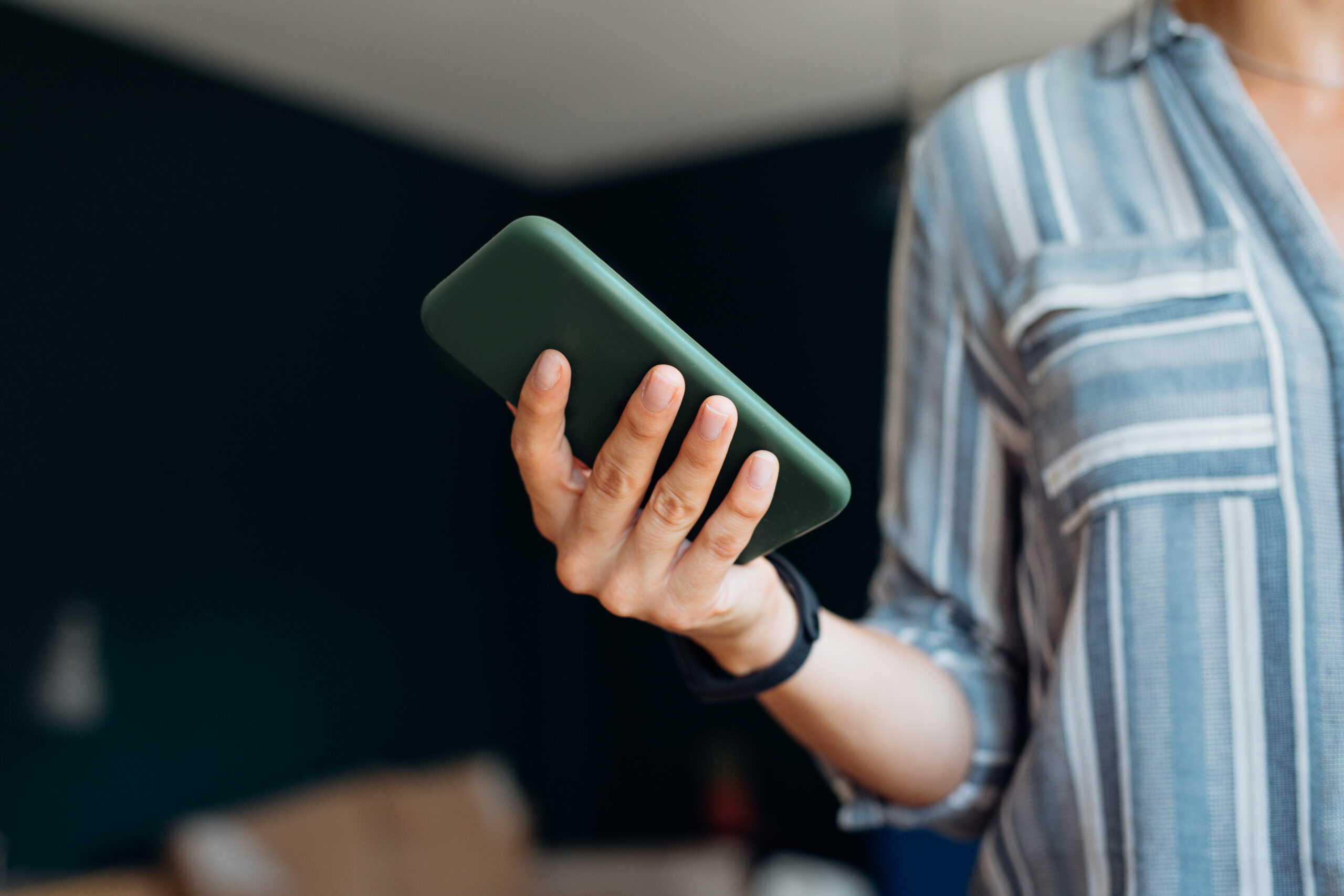Casual young female hands holding using modern smartphone device indoors