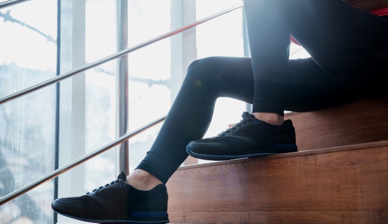 A person wearing leggings sits on the stairs.
