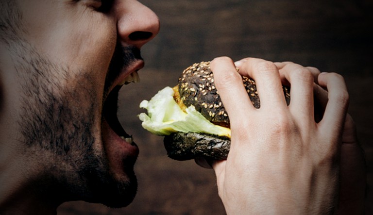 A man opens his jaws, anticipating the delicious sandwich that awaits him.