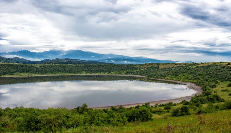 Clouds over a crater lake and blue mountains in Queen Elizabeth National Park in Uganda. 