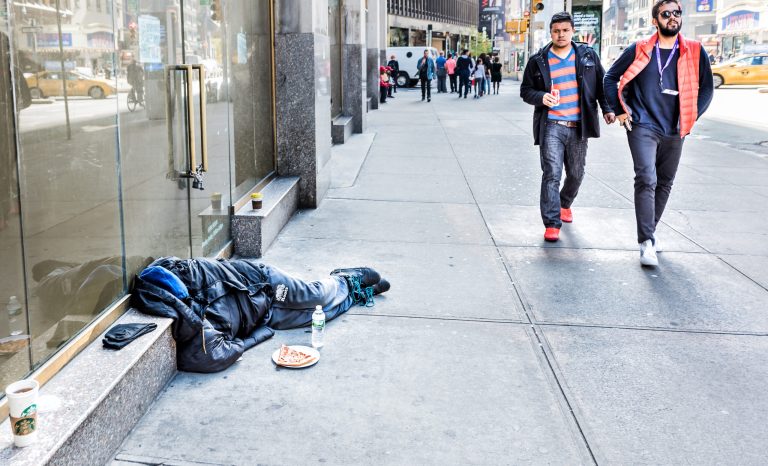 New York City - October 28, 2017: A homeless man sleeping on a Manhattan sidewalk.