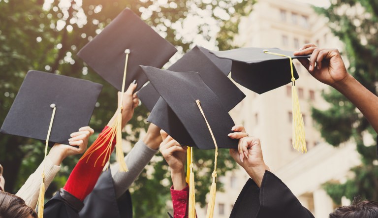 A group of students celebrates their graduation by throwing caps in the air.