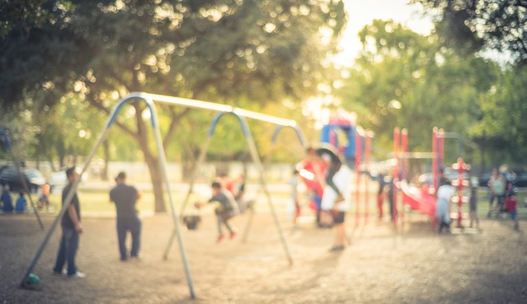 Vintage blurred kids on swing at busy public playground in USA.