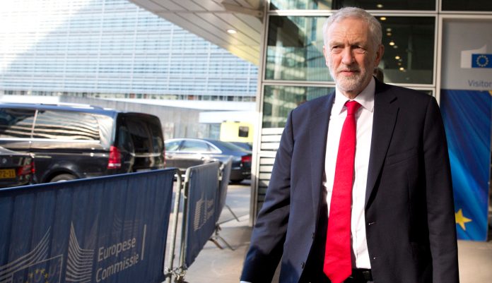 British Labour Party leader Jeremy Corbyn, center, prepares to speak with the media outside EU headquarters in Brussels, Thursday, Feb. 21, 2019.