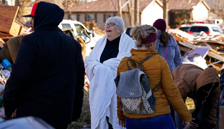 Martha Thomas, wrapped in a table cloth for warmth, reacts as volunteers, who are employees of the Mayfield Consumer Products factory, help her salvage possessions from her destroyed home, in the aftermath of tornadoes that tore through the region, in Mayfield, Kentucky, Monday, Dec. 13, 2021.