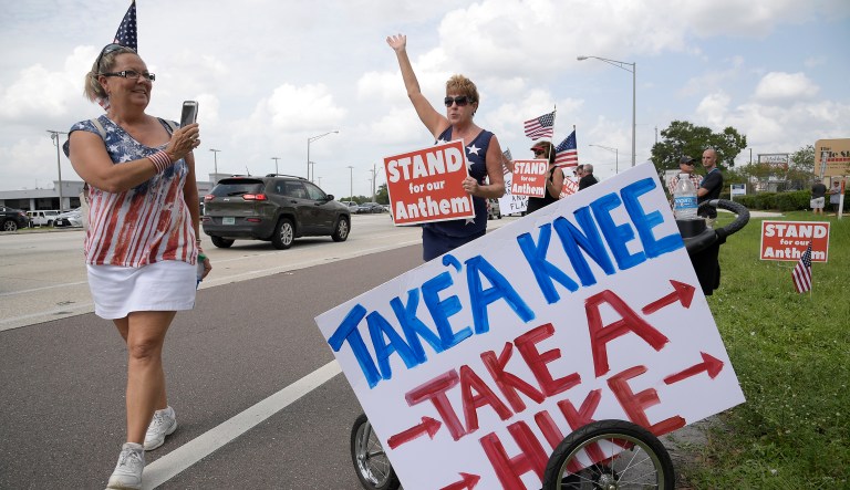 Protesters upset with players kneeling during the national anthem stand along a road leading to Raymond James Stadium before an NFL football game between the Tampa Bay Buccaneers and the New York Giants Sunday, Oct. 1, 2017, in Tampa, Fla.