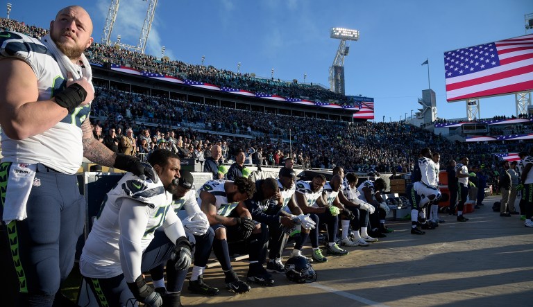 Members of the Seattle Seahawks kneel and sit on the bench during the singing of the national anthem before an NFL football game against the Jacksonville Jaguars Sunday, Dec. 10, 2017, in Jacksonville, Fla.
