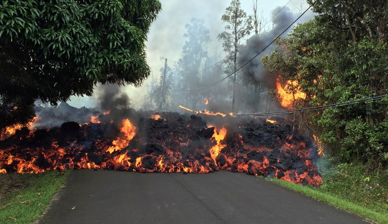 In this Sunday, May 6, 2018 photo provided by the U.S. Geological Survey,  a lava flow moves across Makamae Street in the Leilani Estates subdivision near Pahoa on the island of Hawaii. Kilauea volcano has destroyed more than two dozen homes since it began spewing lava hundreds of feet into the air last week, and residents who evacuated don't know how long they might be displaced. The decimated homes were in the Leilani Estates subdivision, where molten rock, toxic gas and steam have been bursting through openings in the ground created by the volcano.