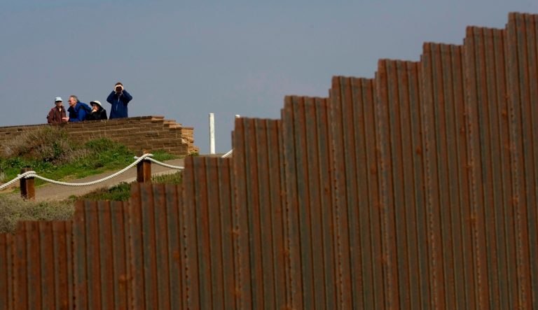 People in U.S. territory look towards Mexico from behind the border wall in Tijuana, Monday, Feb. 18, 2008.