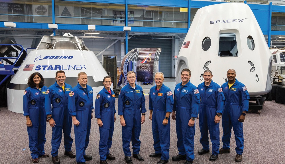 On Aug. 3, NASA announced the astronauts who will ride the first commercial capsules into orbit next year.  From left, Sunita Williams, Josh Cassada, Eric Boe, Nicole Mann, Christopher Ferguson, Douglas Hurley, Robert Behnken, Michael Hopkins and Victor Glover stand in front of Boeing’s CST-100 Starliner and SpaceX’s Crew Dragon capsules at the Kennedy Space Center in Florida. 