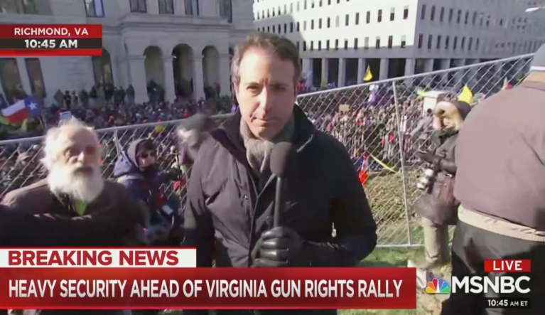 A man curses at Gabe Gutierrez during his live shot on MSNBC from Virginia gun rally on 1/20