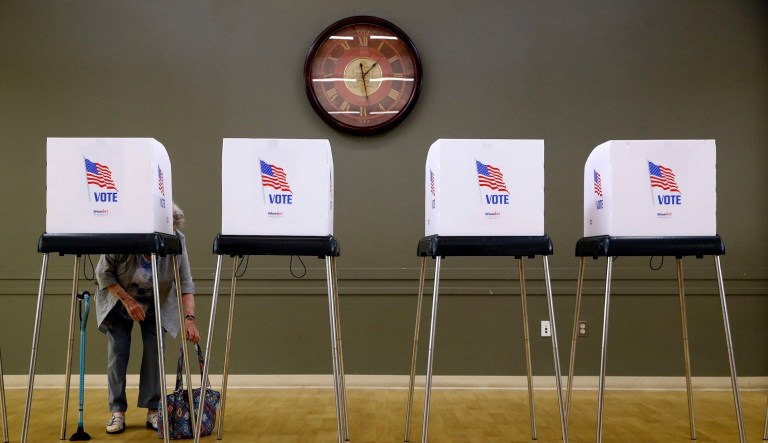 A woman places her purse at her feet as she prepares to vote at a polling place on June 26, 2018, in Silver Spring, Md.