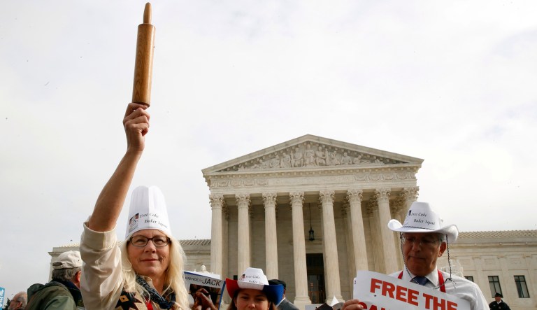 Mary Torres of Falls Church, Va., left, with her daughter Maria Torres, and Eugene Delgaudio, holds up a rolling pin in support of cake artist Jack Phillips, while outside of the Supreme Court, Tuesday, Dec. 5, 2017, during the 'Masterpiece Cakeshop v. Colorado Civil Rights Commission' case in Washington.