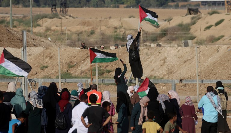 A Palestinian protester woman hangs the national flag while climbing the fence of Gaza Strip's border with Israel, during a protest east of Gaza City, Tuesday, July 3, 2018.