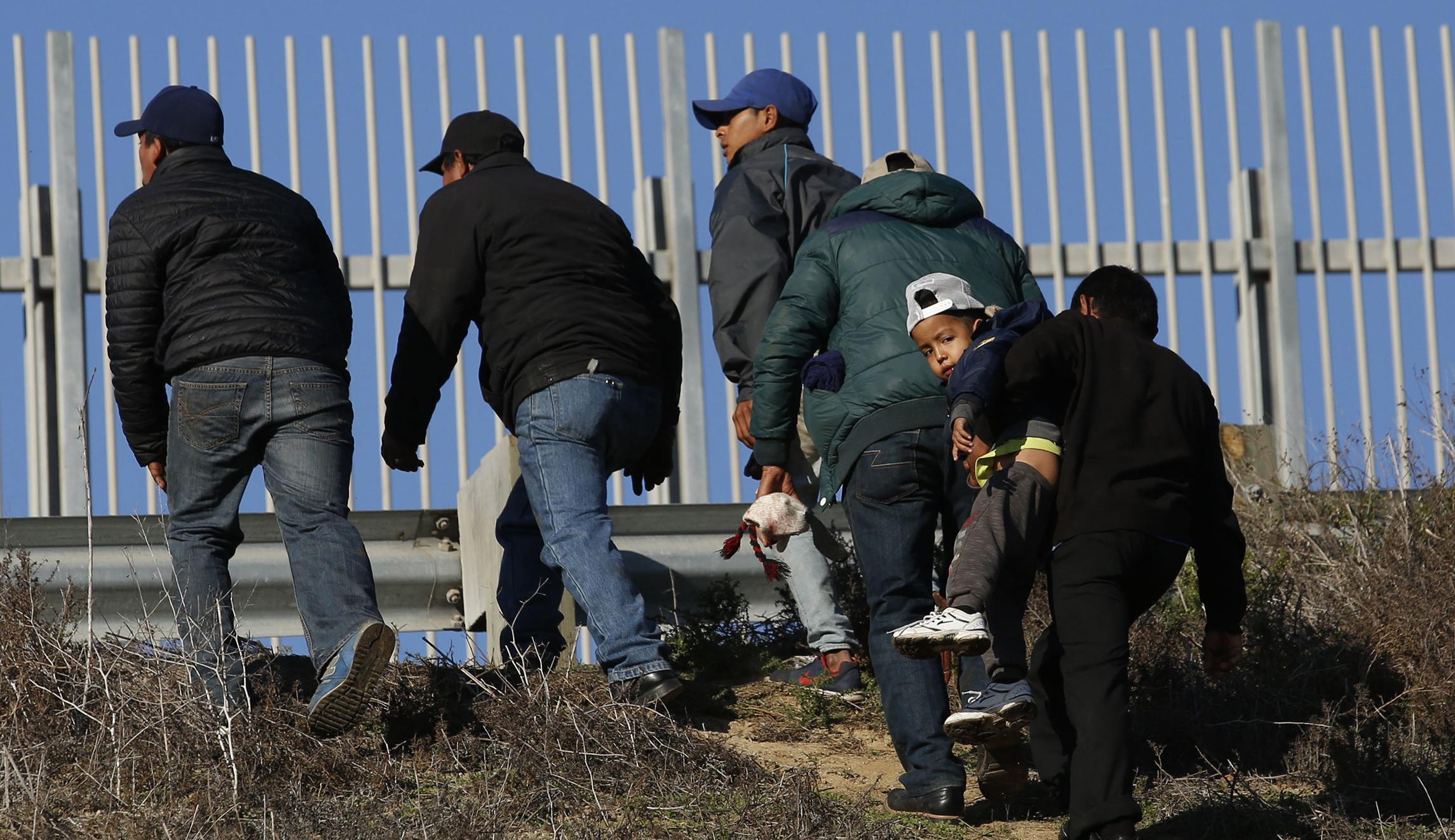 Migrants on Mexico-California border seen wearing shirts begging Biden to let them in